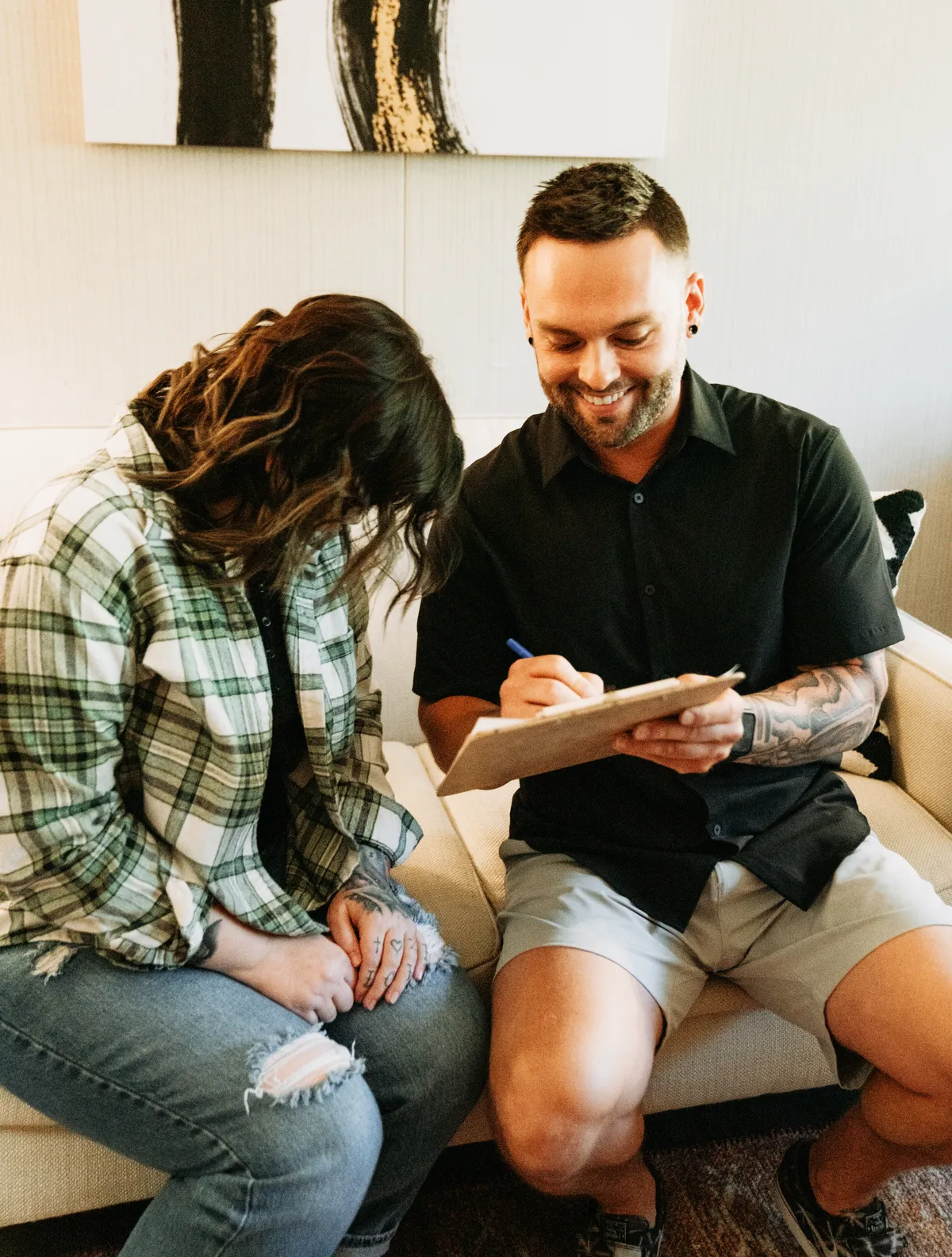 A Redpoint counselor taking notes beside a client during a consultation on a couch.