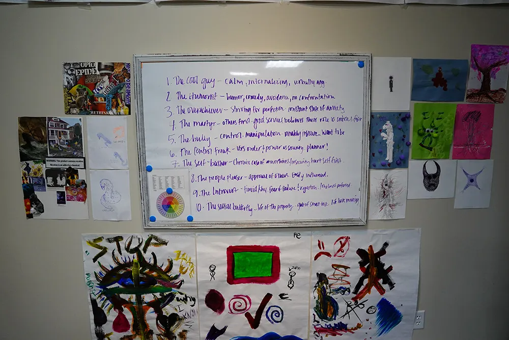 A whiteboard listing ten defensive roles, surrounded by client artwork and a collage.