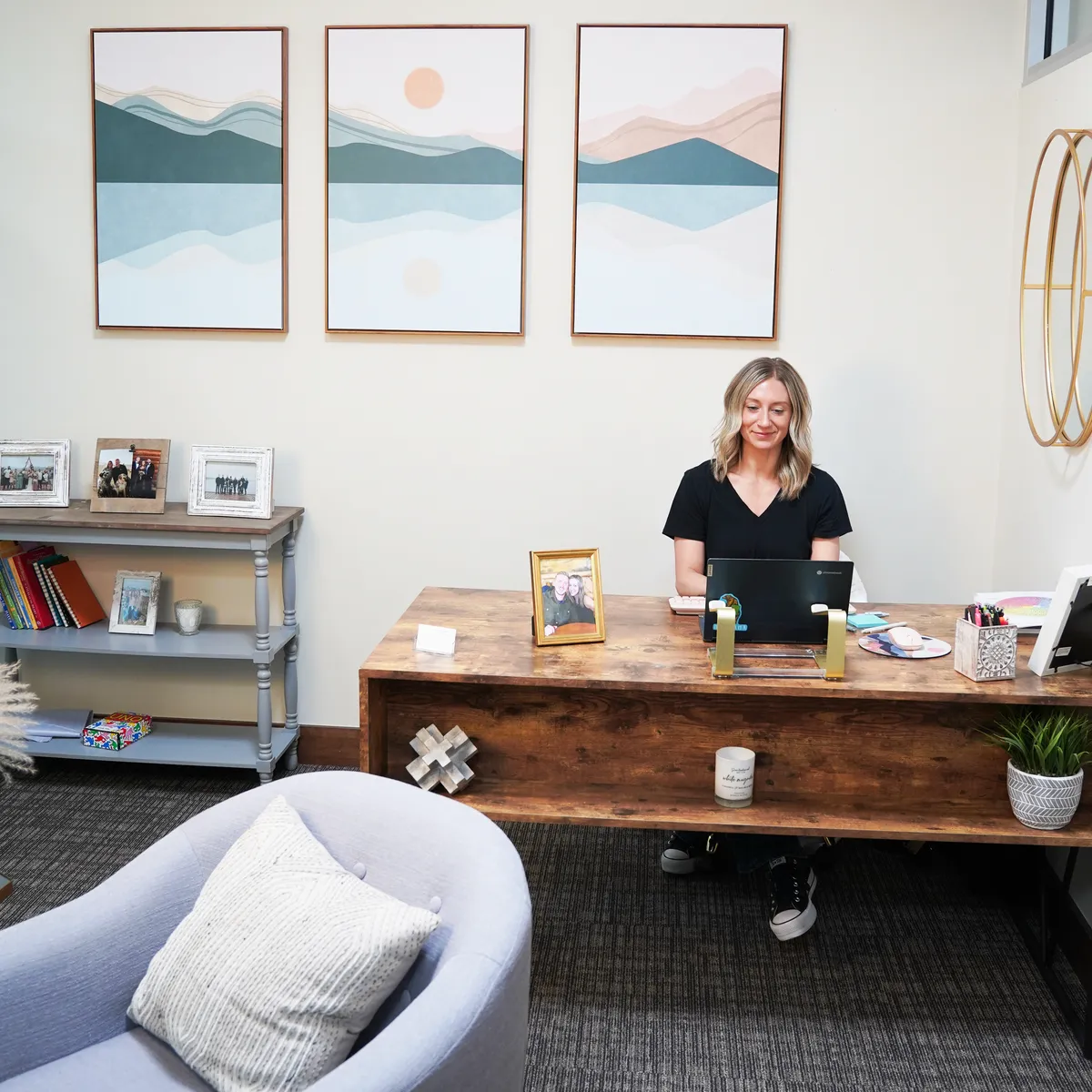A Redpoint staff member working at a laptop on a wood desk in a private office, mountain artwork on the wall behind.